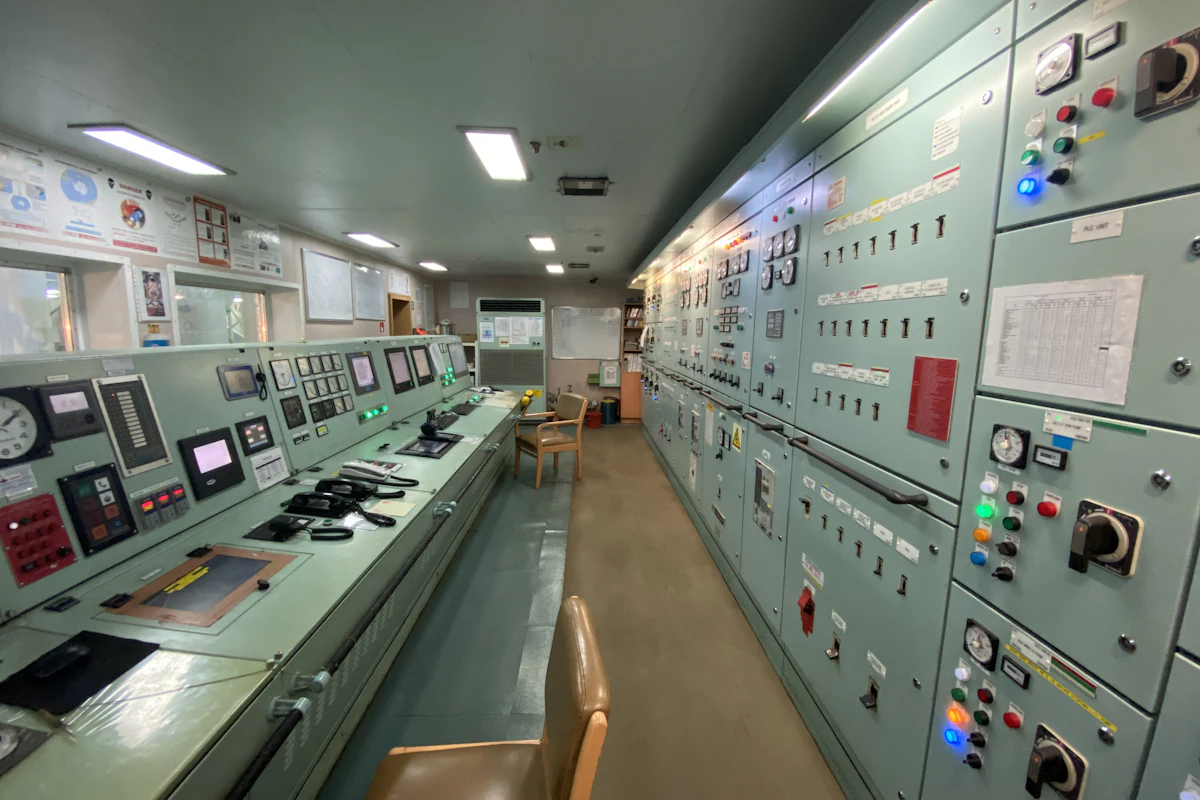 Industrial control room with rows of control panels, gauges and operator consoles