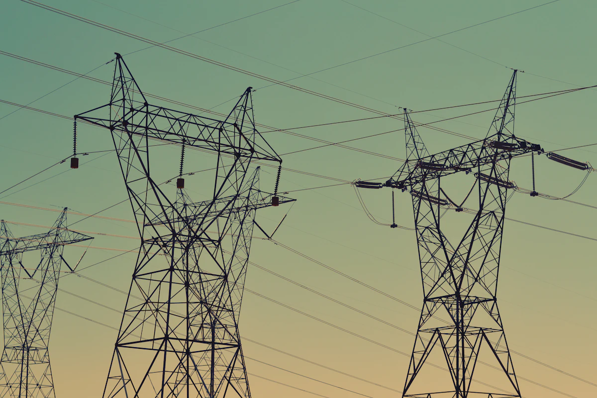 High-voltage transmission towers silhouetted against a green sky