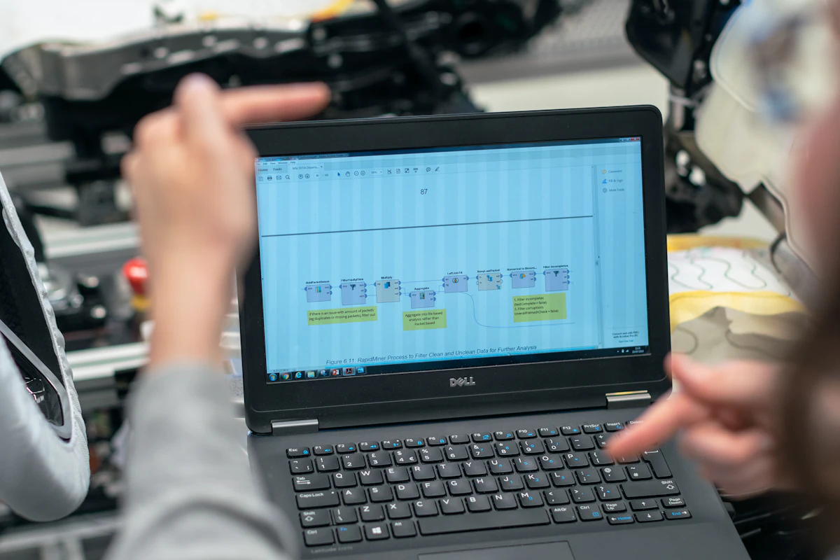 Laptop showing engineering software on a workbench beside industrial equipment